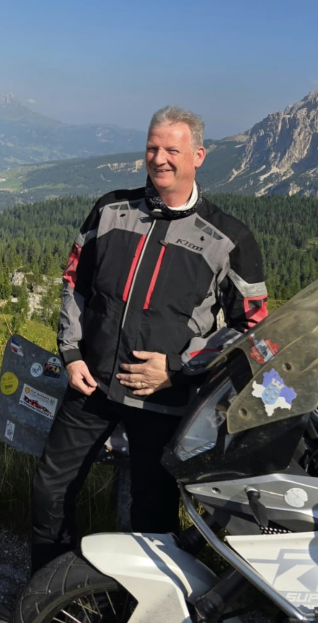 Mick Nolan standing beside his motorcycle in the Dolomites.